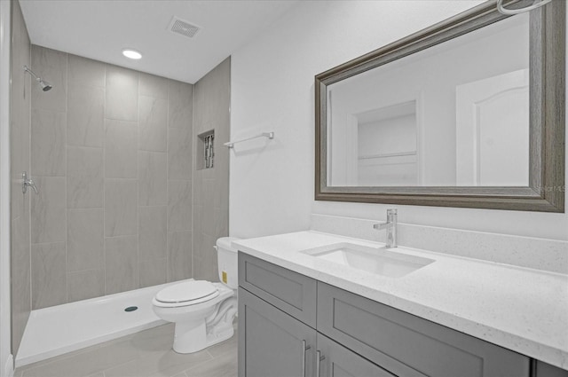 bathroom featuring vanity, toilet, and tiled shower