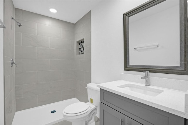 bathroom featuring vanity, tiled shower, and toilet