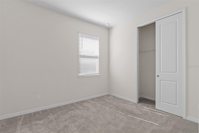 unfurnished bedroom featuring light carpet and a closet