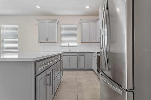 kitchen featuring tasteful backsplash, stainless steel appliances, gray cabinets, and light tile patterned floors