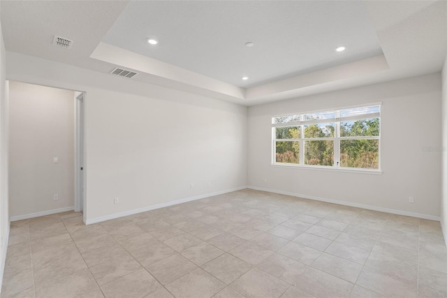 tiled spare room with a raised ceiling