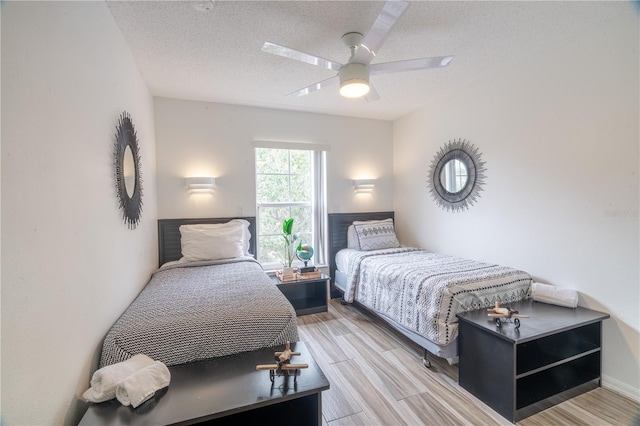 bedroom with a textured ceiling, ceiling fan, and light hardwood / wood-style floors