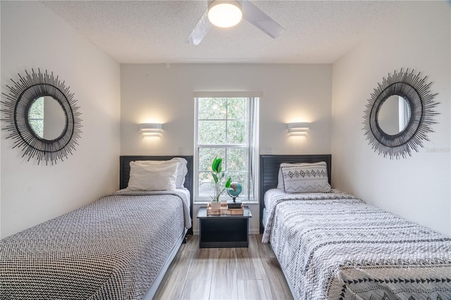 bedroom with ceiling fan, wood-type flooring, and a textured ceiling