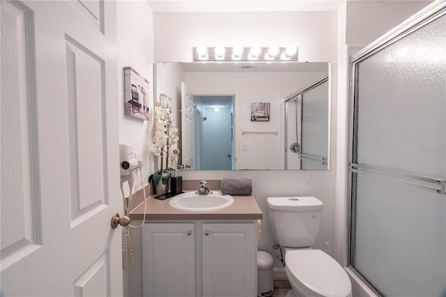 bathroom with vanity, a shower with door, and toilet