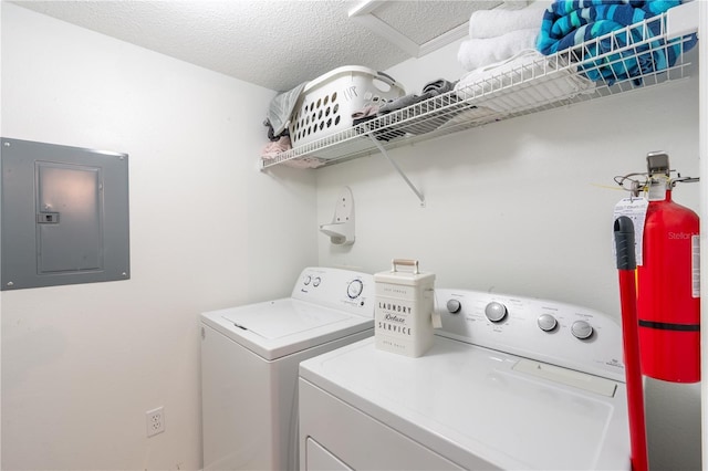 laundry room with a textured ceiling, electric panel, and washing machine and clothes dryer