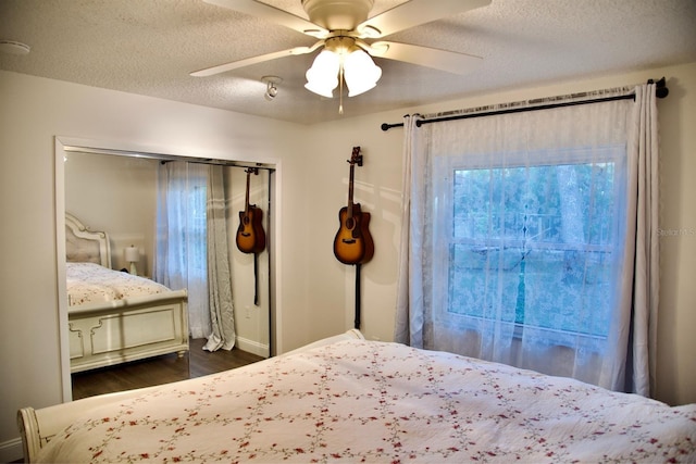 bedroom with ceiling fan, dark hardwood / wood-style floors, a closet, and a textured ceiling