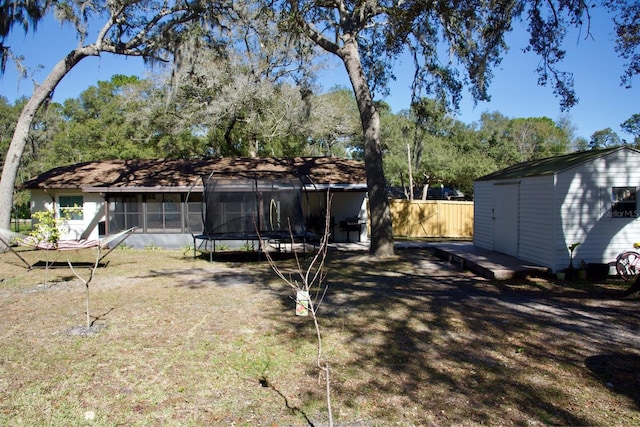 view of yard featuring a storage unit, a sunroom, and a trampoline