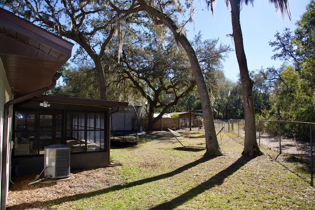 view of yard featuring central AC unit, a sunroom, a trampoline, and a playground