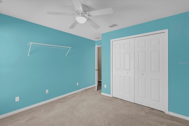 unfurnished bedroom with ceiling fan, light colored carpet, and a closet