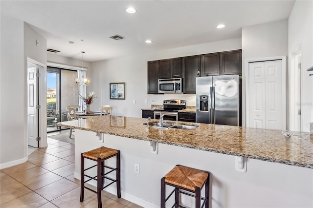 kitchen with pendant lighting, light stone counters, a breakfast bar area, and appliances with stainless steel finishes