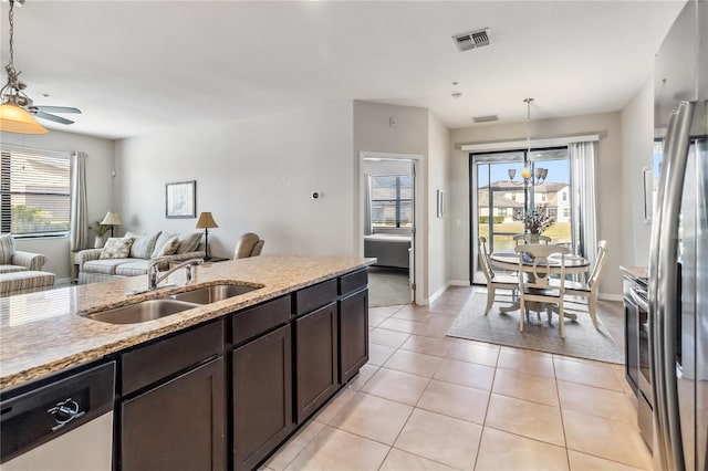 kitchen with appliances with stainless steel finishes, sink, hanging light fixtures, and light tile patterned floors