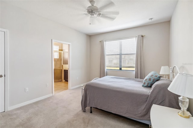 bedroom with ceiling fan, light colored carpet, and ensuite bath