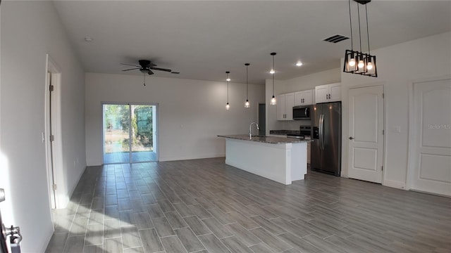 kitchen featuring sink, appliances with stainless steel finishes, white cabinets, a center island with sink, and decorative light fixtures