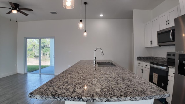 kitchen featuring sink, hanging light fixtures, stainless steel appliances, and an island with sink