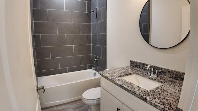 full bathroom featuring vanity, hardwood / wood-style floors, tiled shower / bath combo, and toilet