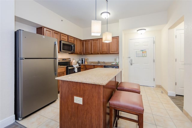 kitchen featuring a breakfast bar area, a center island, hanging light fixtures, light tile patterned floors, and appliances with stainless steel finishes