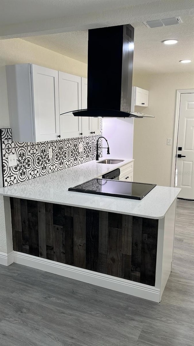 kitchen with tasteful backsplash, white cabinetry, sink, light hardwood / wood-style floors, and kitchen peninsula