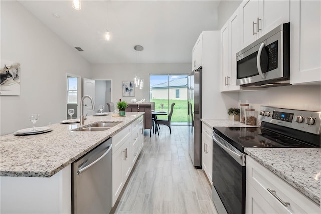 kitchen with appliances with stainless steel finishes, pendant lighting, white cabinetry, sink, and light stone counters