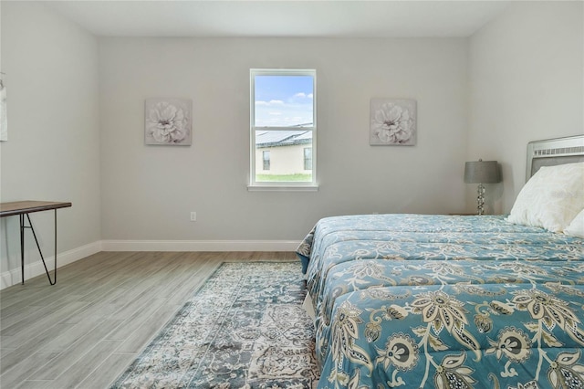 bedroom featuring hardwood / wood-style flooring and a wall mounted AC