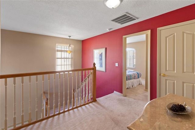 hall with light carpet and a textured ceiling