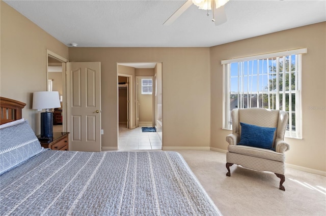 bedroom with light colored carpet, ceiling fan, and ensuite bathroom