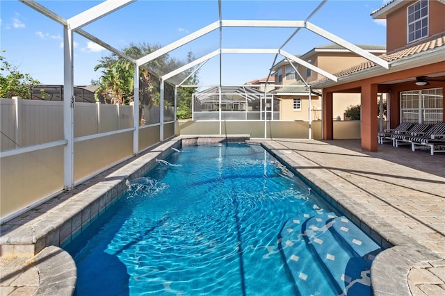 view of swimming pool with a patio, pool water feature, ceiling fan, and a lanai