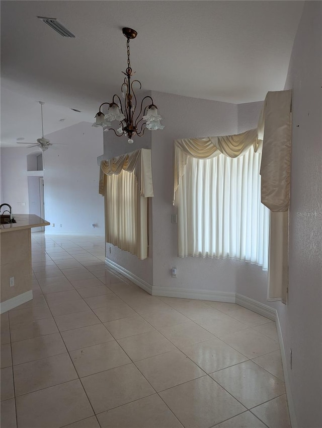 unfurnished dining area with ceiling fan with notable chandelier and light tile patterned flooring