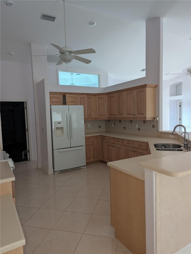 kitchen with high vaulted ceiling, sink, decorative backsplash, white fridge with ice dispenser, and light tile patterned floors