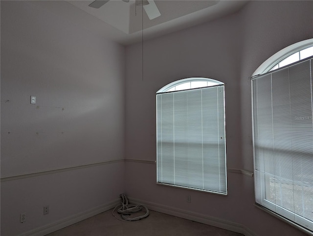 empty room with tile patterned flooring, a wealth of natural light, and ceiling fan