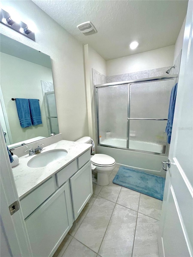 full bathroom with vanity, bath / shower combo with glass door, a textured ceiling, and toilet