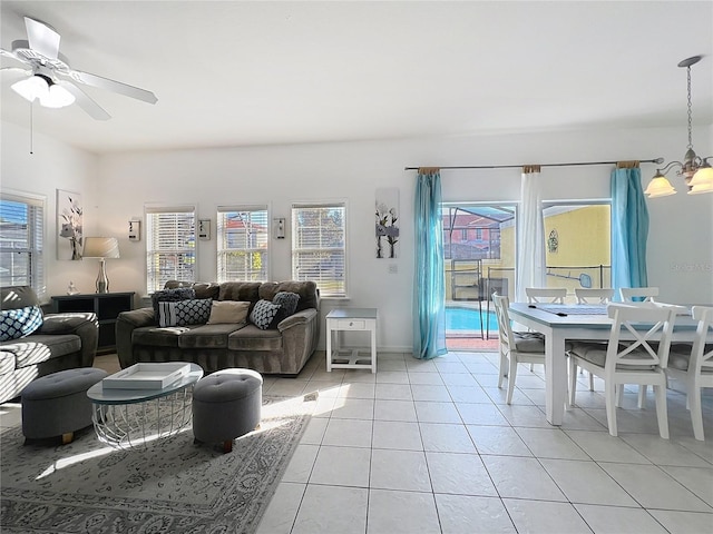 tiled living room with ceiling fan with notable chandelier