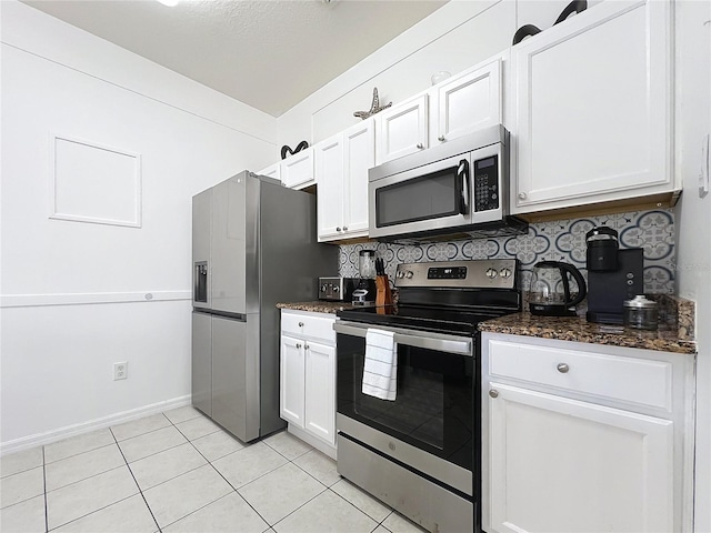 kitchen with stainless steel appliances, light tile patterned floors, white cabinets, and decorative backsplash