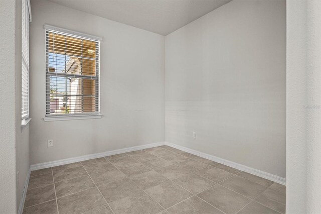 unfurnished room featuring tile patterned floors and baseboards