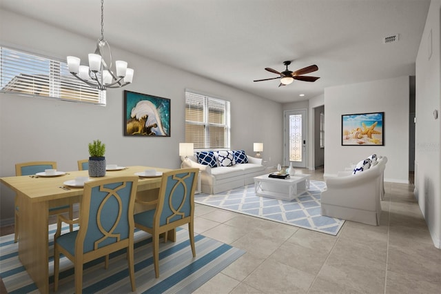 living room with light tile patterned floors, visible vents, ceiling fan with notable chandelier, and baseboards