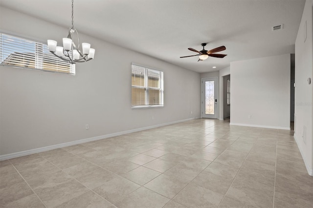 empty room with visible vents, light tile patterned flooring, ceiling fan with notable chandelier, and baseboards