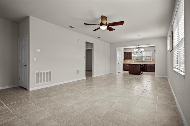 unfurnished living room with light tile patterned floors, visible vents, and ceiling fan with notable chandelier