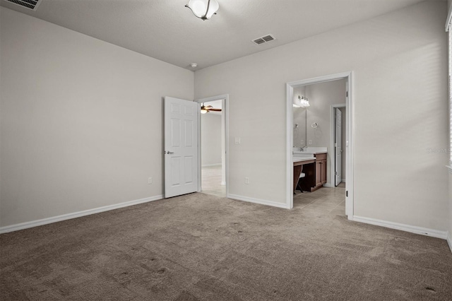 unfurnished bedroom featuring light carpet, visible vents, ensuite bath, and baseboards