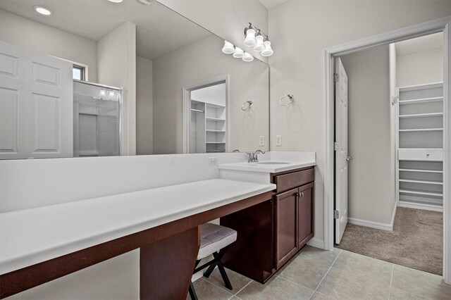 bathroom with tile patterned floors, a walk in closet, an enclosed shower, and vanity