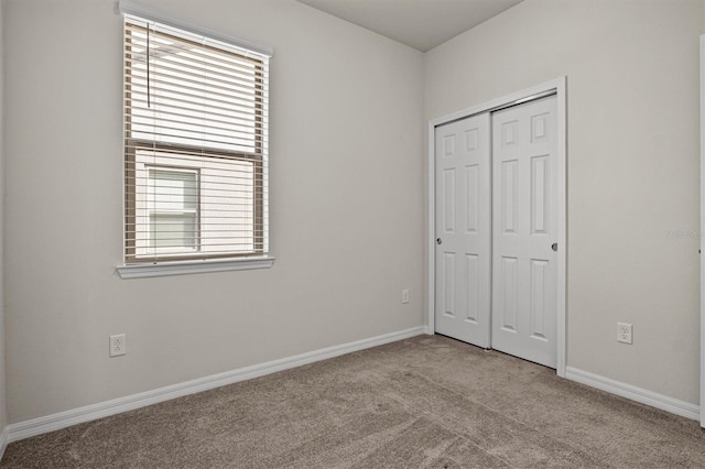 unfurnished bedroom with carpet, baseboards, and a closet