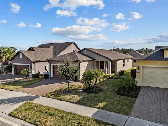 ranch-style house featuring a front lawn, decorative driveway, an attached garage, and stucco siding