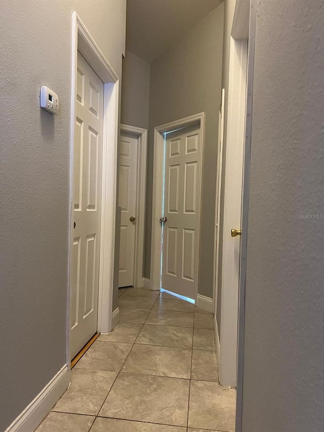 hall featuring baseboards and light tile patterned floors