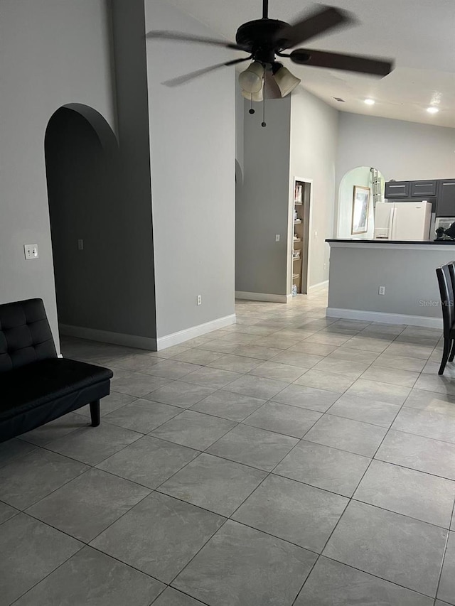 living area with baseboards, arched walkways, a ceiling fan, and light tile patterned flooring