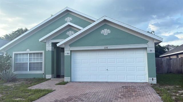 228 Remington Pl, Haines City, FL 33844 - ranch-style house featuring decorative driveway, an attached garage, and stucco siding