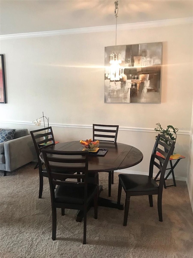 dining area with carpet floors, ornamental molding, and a notable chandelier