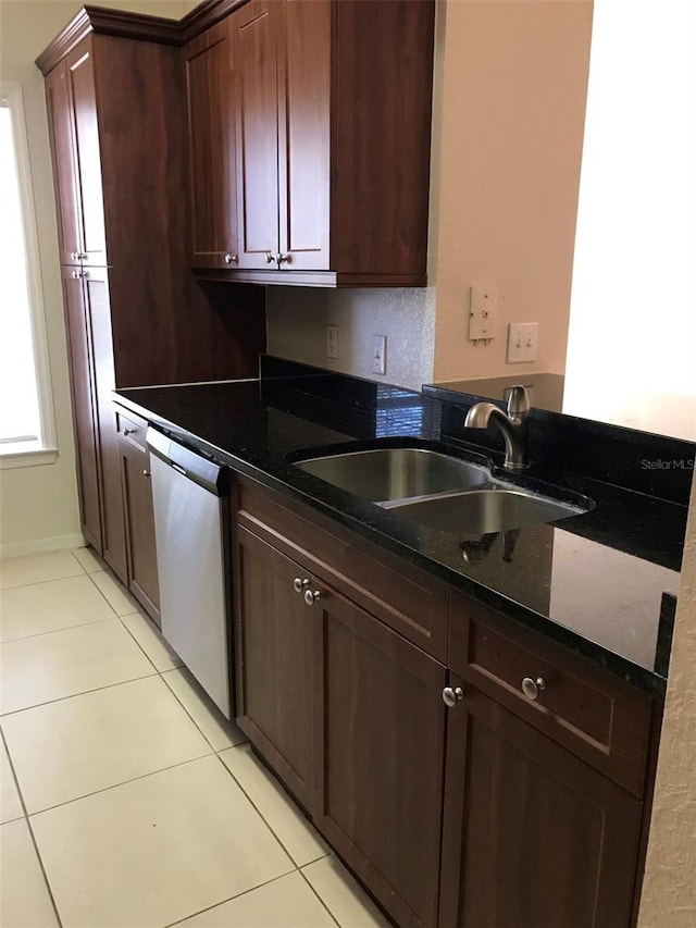 kitchen featuring light tile patterned flooring, sink, dark stone countertops, stainless steel dishwasher, and dark brown cabinets