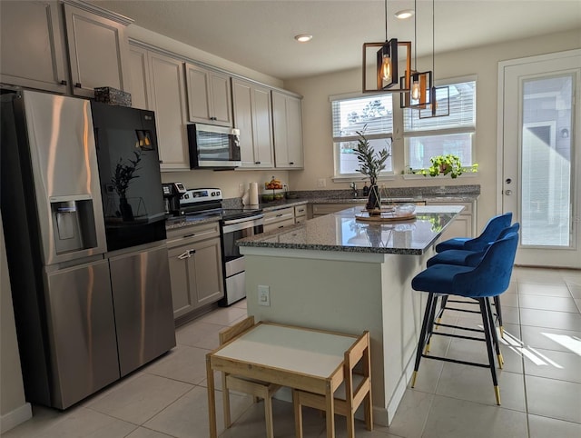 kitchen featuring stainless steel appliances, light tile patterned floors, a kitchen island, and gray cabinetry