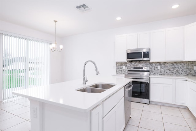 kitchen with sink, hanging light fixtures, appliances with stainless steel finishes, an island with sink, and white cabinets