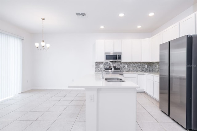 kitchen with light tile patterned floors, appliances with stainless steel finishes, an island with sink, pendant lighting, and white cabinets