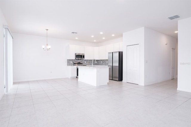 kitchen featuring white cabinetry, a center island with sink, appliances with stainless steel finishes, pendant lighting, and decorative backsplash