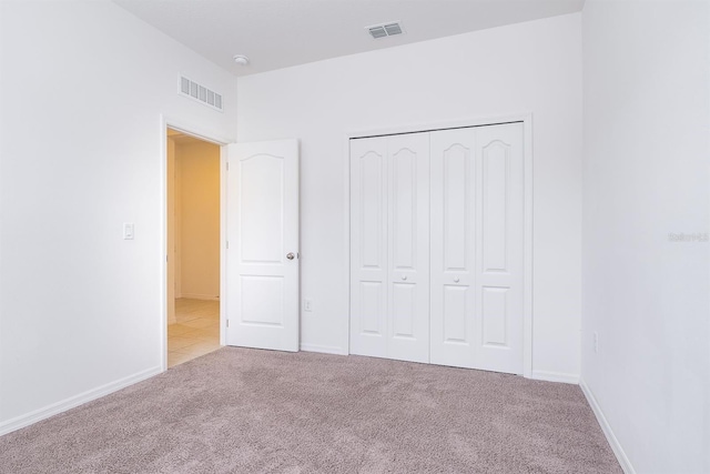 unfurnished bedroom with light carpet and a closet